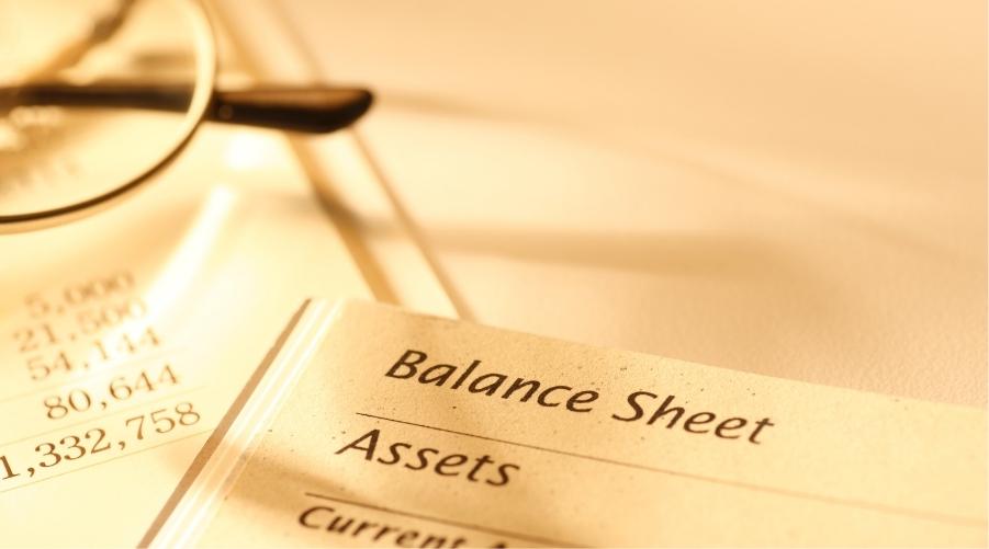 Image of balance sheet pages underneath a pair of glasses